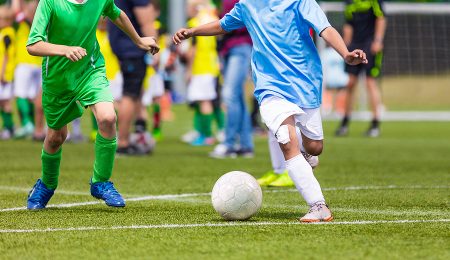 Young boys playing soccer game. Kids having fun in sport. Happy kids compete in football game. Running soccer players. Competition between players running and kicking football ball. Football school